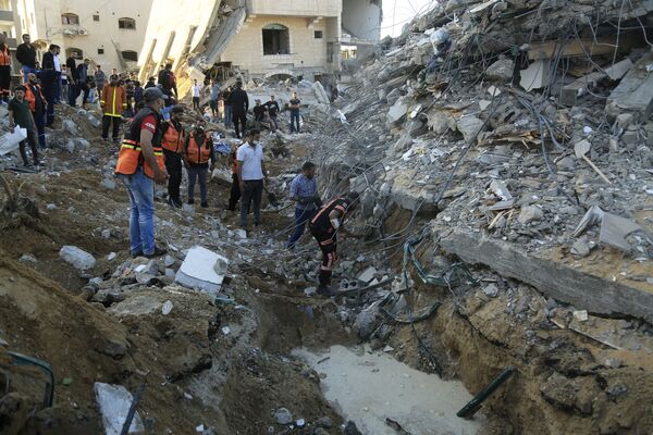 فلسطينيون يتجمعون حول مواقع منازلهم المقصوفة في بيت لاهيا، شمال قطاع غزة، فلسطين 13 مايو 2021 - سبوتنيك عربي