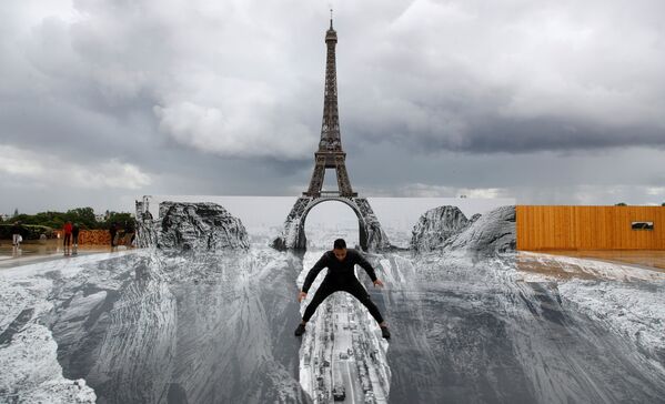 رجل خلال التقاط صورة له، يقف على عمل فني عملاق للفنان الفرنسي جي آر (JR ) مثبت في ميدان تروكاديرو أمام برج إيفل في باريس، فرنسا ، 19 مايو 2021 - سبوتنيك عربي
