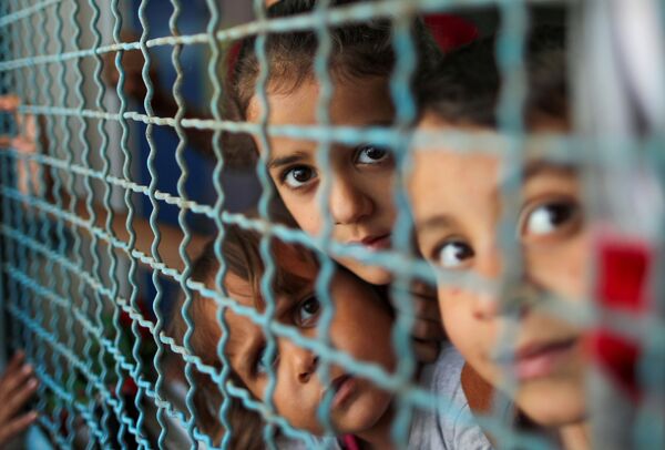 أطفال ينظرون من نافذة مدرسة الأنروا. يذكر أنه نزح ما يقرب 34 ألف من أهالي قطاع غزة إلى مدراس الأونروا بعد قصف الطيران الحربي الإسرائيلي منازلهم، فلسطين بتاريخ 18 مايو 2021 - سبوتنيك عربي