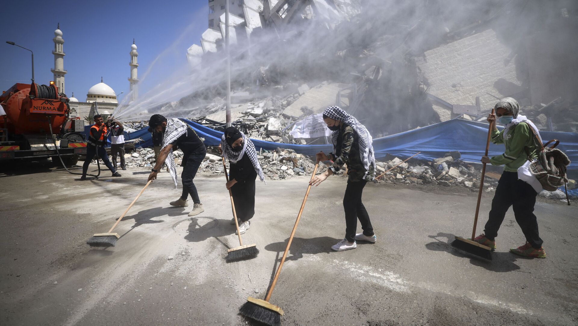 متطوعون فلسطينيون وعمال بلدية يقومون بإزالة أنقاض مجمع برج هنادي، الذي دمرته الغارات الإسرائيلية في الحرب الأخيرة، في حي الرمال بمدينة غزة، في 25 مايو 2021 - سبوتنيك عربي, 1920, 30.05.2021