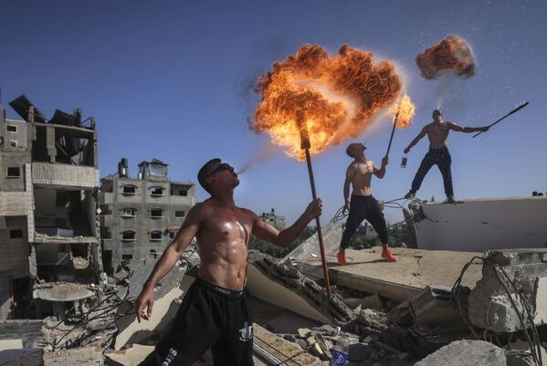 أعضاء فريق بار وولف الفلسطيني من غزة يؤدون عرضًا ناريًا على أنقاض مبنى دمرته الغارات الجوية الإسرائيلية، 26 مايو 2021 - سبوتنيك عربي