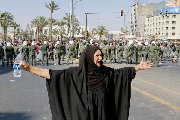 امرأة تشير إلى متظاهرين يشاركون في مظاهرة مناهضة للحكومة في بغداد، العراق، 25 مايو 2021 - سبوتنيك عربي