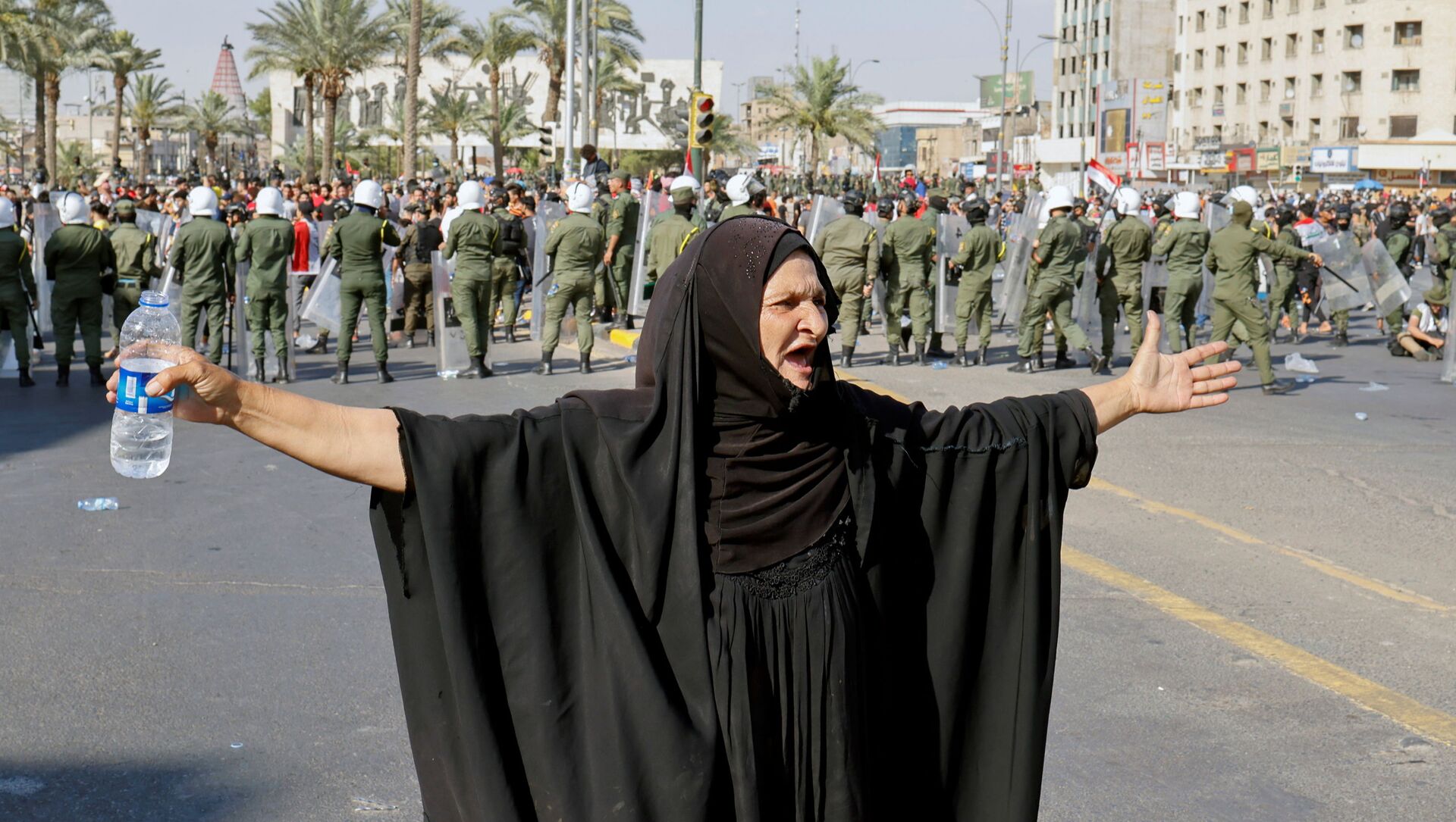 امرأة تشير إلى متظاهرين يشاركون في مظاهرة مناهضة للحكومة في بغداد، العراق، 25 مايو 2021 - سبوتنيك عربي, 1920, 27.07.2021