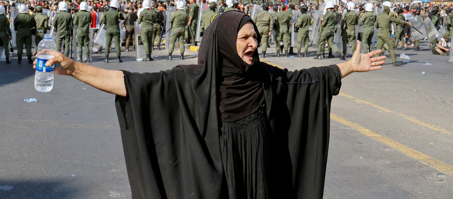 امرأة تشير إلى متظاهرين يشاركون في مظاهرة مناهضة للحكومة في بغداد، العراق، 25 مايو 2021 - سبوتنيك عربي, 1920, 21.06.2021