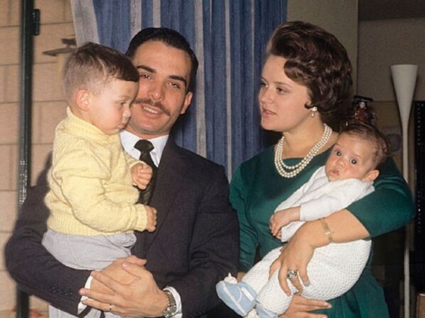 ملك الأردن السابق حسين وزوجته الأميرة منى مع طفليهما الأمير عبدالله الثاني (ملك الأردن الحالي، يسار الصورة)، والأمير فيصل (يمين الصورة)، عام 1964 - سبوتنيك عربي