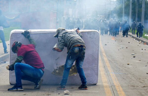 متظاهرون يختبئون خلف فراش أثناء الاشتباكات مع شرطة مكافحة الشغب، التي اندلعت خلال احتجاجات ضد حكومة الرئيس الكولومبي إيفان دوكي في فاتاتيفا، كولومبيا، في 31 مايو 2021 - سبوتنيك عربي