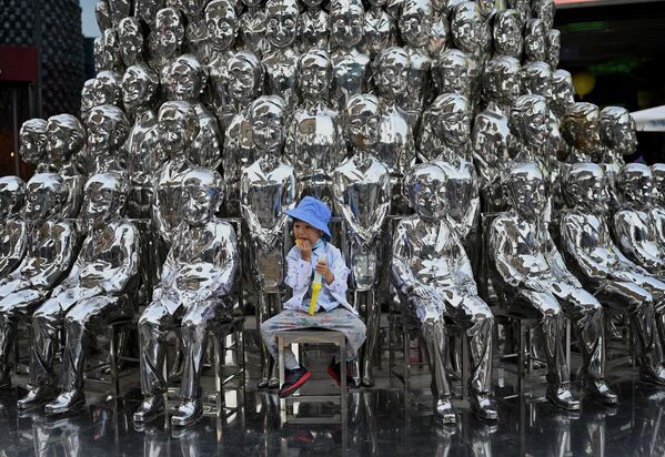 صبي يجلس على كرسي بين منحوتات معروضة في مركز تسوق في يوم الطفل العالمي في بكين في الأول من يونيو 2021، بعد يوم من إعلان الصين بالسماح للأزواج بإنجاب ثلاثة أطفال. - سبوتنيك عربي