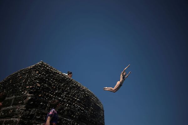 فتاة تقفز إلى مياه البحر حيث يستمتع الناس بالطقس الحار على شاطئ برايتون في برايتون، بريطانيا، 1 يونيو 2021 - سبوتنيك عربي
