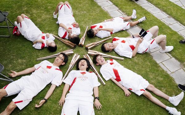 المشاركون في سلسلة تتابع شعلة أولمبياد طوكيو يستلقون في دائرة خلال استراحة في توياما باليابان في 3 يونيو 2021 - سبوتنيك عربي