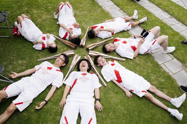 المشاركون في سلسلة تتابع شعلة أولمبياد طوكيو يستلقون في دائرة خلال استراحة في توياما باليابان في 3 يونيو 2021 - سبوتنيك عربي