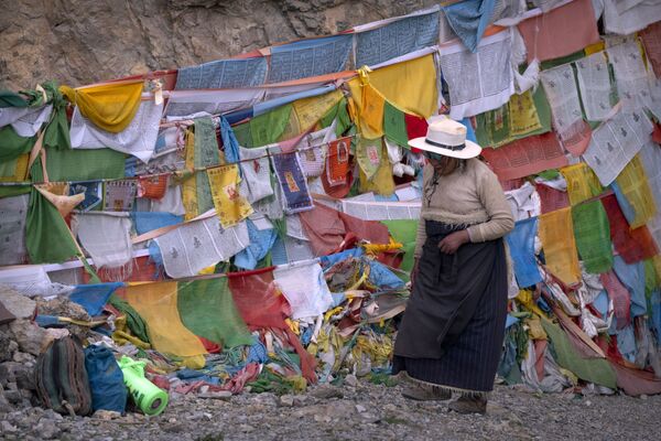 امرأة تبتية تسير أمام أعلام الصلاة في ضريح بوذي في نامتسو، في منطقة التبت ذاتية الحكم بغرب الصين، خلال زيارة نظمتها الحكومة للصحفيين الأجانب، 2 يونيو 2021 - سبوتنيك عربي