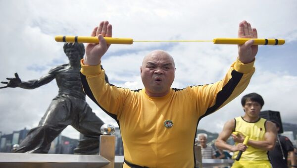 لاعب كونغ فو يمارس بعض الحركات القتالية أمام تمثال لمدرب الفنون القتالية الصين الراحل بروس لي - سبوتنيك عربي