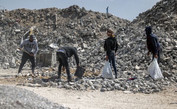 عمال يكسرون الأنقاض لإعادة تدوير مواد البناء من ركام المباني في حي الشجاعية، بعد تبادل إطلاق النار بين قطاع غزة وإسرائيل في مايو الماضي، 5 يونيو 2021 - سبوتنيك عربي