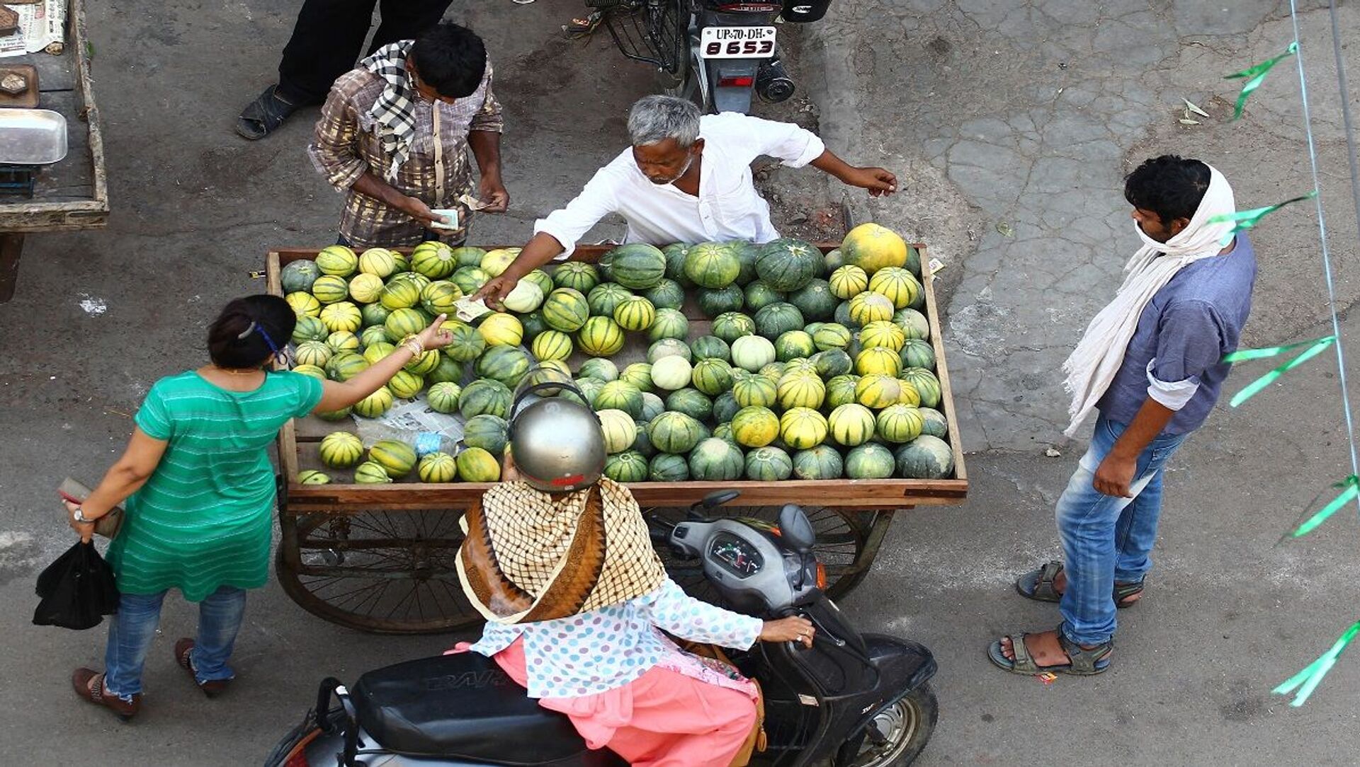 بائع متجور يبيع ثمار الشمام إلى مجموعة من الناس في الهند - سبوتنيك عربي, 1920, 19.11.2021