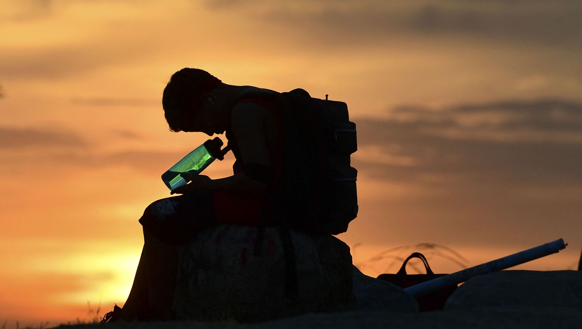 طفل ينظر إلى زجاجة المياه الخاصة به على خلفية غروب الشمس في لوس أنجلوس،  مع ارتفاع درجات الحرارة في موجة الحر في بداية موسم الحر في كاليفورنيا، الولايات المتحدة،  في 15 يونيو 2021 - سبوتنيك عربي, 1920, 05.07.2021