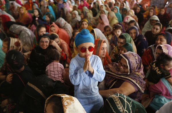 طفل من الديانة السيخية، يقف بجانب والدته في حفل لإحياء الذكرى الـ 415 لاستشهاد غورو أرجان ديف جي، في غورودوارا ديرا صاحب، في لاهو ، باكستان، 16 يونيو 2021 - سبوتنيك عربي