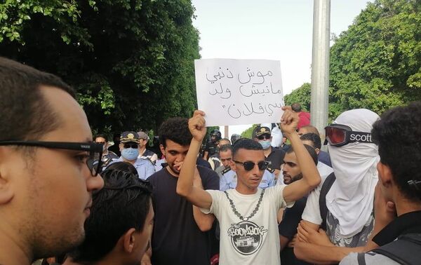 شاب يرفع لافتة خلال مسيرة في شارع الحبيب بورقيبة بتونس للتنديد بقمع الشرطة للاحتجاجات الأخيرة، 18 يونيو/ حزيران 2021 - سبوتنيك عربي
