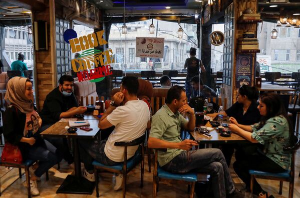 الزبائن يجلسون في مقهى، حيث تُقدم قهوة مجانية للأشخاص الذين تلقوا لقاحاً ضد مرض كوفيد-19 في بغداد، العراق ، 22 مايو 2021 - سبوتنيك عربي