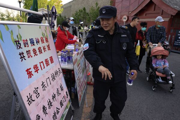 حارس أمن يتلقى ملصقًا يعلن أنه تم تطعيمه ضد فيروس كورونا خارج مدخل المدينة المحرمة في بكين، الصين 14 أبريل 2021 - سبوتنيك عربي