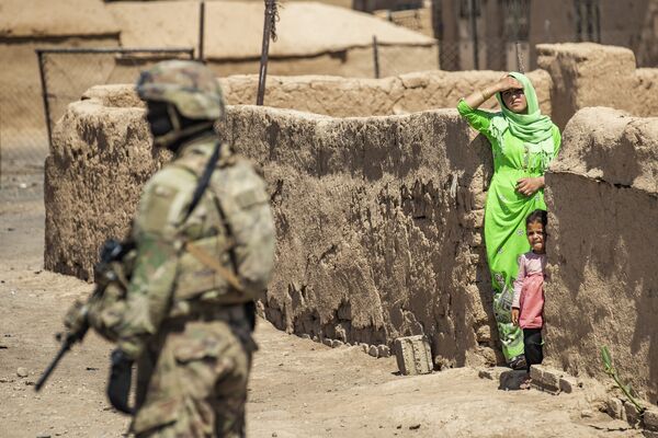   امرأة وطفل ينظران إلى جندي أمريكي يقف خلال دورية عسكرية أمريكية في الرميلان، في محافظة الحسكة شمال شرق سوريا، 22 يونيو 2021 - سبوتنيك عربي