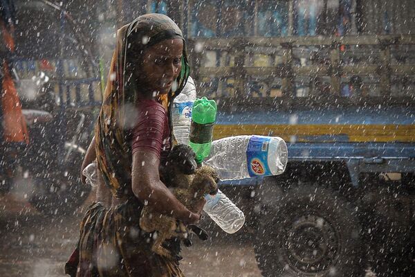 امرأة تبحث عن مأوى أثناء هطول أمطار غزيرة في دكا، بنغلادش 21 يونيو 2021 - سبوتنيك عربي