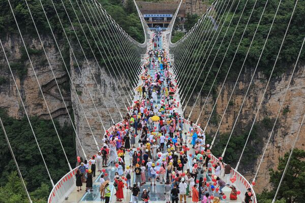 تُظهر الصورة الجوية التي التقطت في 20 يونيو 2021 ، أشخاصًا يسيرون على ممر جسر ذو قاع زجاجي في تشانغجياجيه، بمقاطعة هونان وسط الصين - سبوتنيك عربي