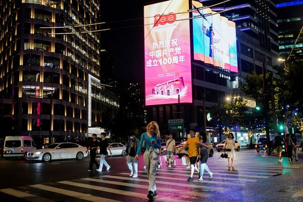 مواطنون يسيرون في شوارع مدينة شنغهاي على خلفية لافتة تحيي الذكرى المئوية لتأسيس الحزب الشيوعي الصيني، الصين،  15 يونيو 2021 - سبوتنيك عربي