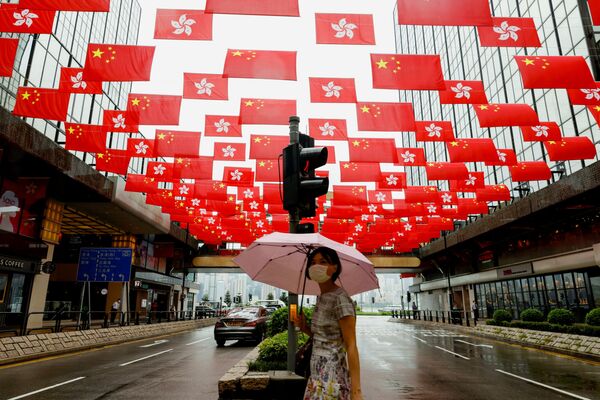 امرأة تسير في أحد شوارع هونغ كونغ مزينة بأعلام حمراء بمناسبة الذكرى المئوية لتأسيس الحزب الشيوعي الصيني، الصين، 28 يونيو 2021 - سبوتنيك عربي