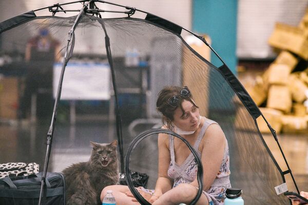 امرأة وقطتها تستريحان داخل خيمة في محطة تبريد مركزي للمؤتمرات في أوريغون، بورتلاند على خلفية موجة حر في معظم أنحاء الولايات المتحدة،  28 يونيو 2021 - سبوتنيك عربي