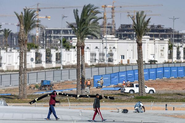 عمال بناء يسيرون على خلفية أعمال بناء في العاصمة الإدارية الجديدة، مصر 7 مارس 2021 - سبوتنيك عربي