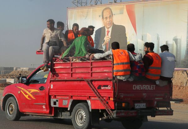 عمال البناء يمرون بجوار لافتة للرئيس المصري عبدالفتاح السيسي في العاصمة الإدارية الجديدة، مصر 5 يوليو 2021 - سبوتنيك عربي