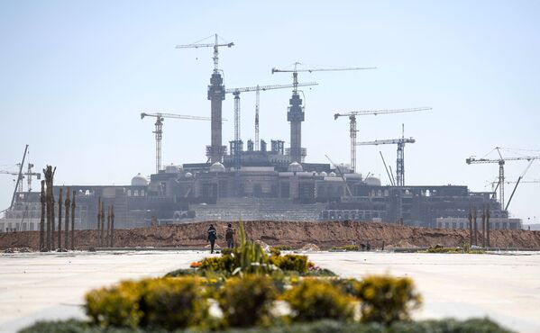 عمال البناء يسيرون على خلفية منظر عام لأعمال البناء في العاصمة الإدارية الجديدة، مصر 7 مارس 2021 - سبوتنيك عربي