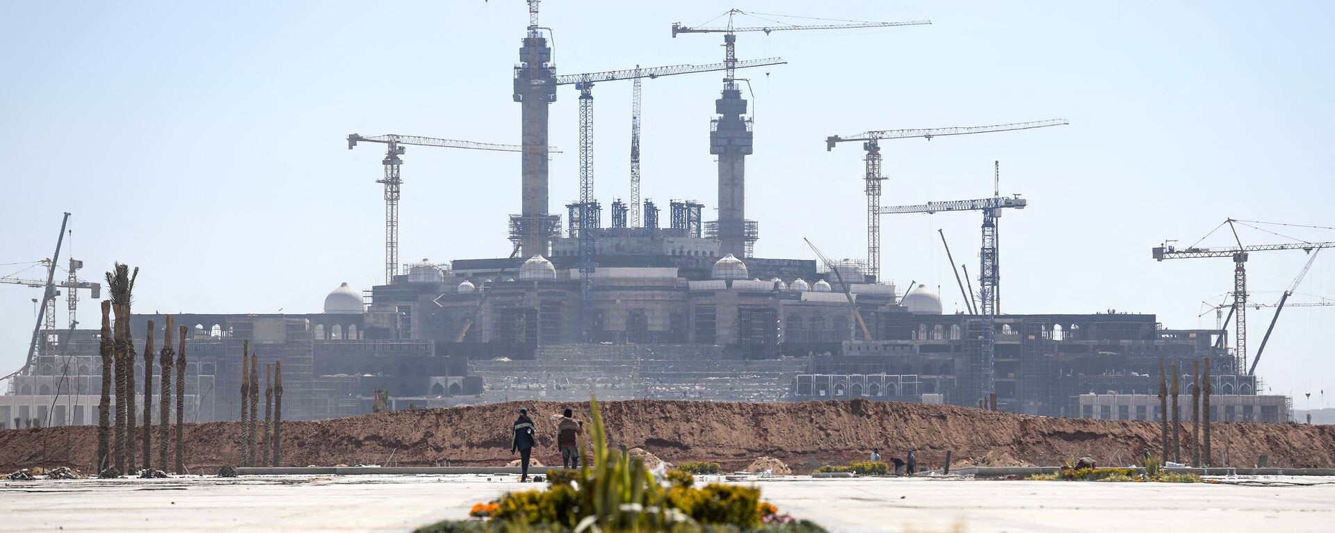 عمال البناء يسيرون على خلفية منظر عام لأعمال البناء في العاصمة الإدارية الجديدة، مصر 7 مارس 2021 - سبوتنيك عربي, 1920, 06.07.2021