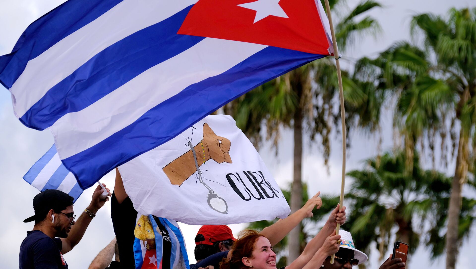 المهاجرون في ليتل هافانا يلوحون بالأعلام الكوبية أثناء ردهم على تقارير الاحتجاجات في كوبا ضد الاقتصاد المتدهور - سبوتنيك عربي, 1920, 12.07.2021