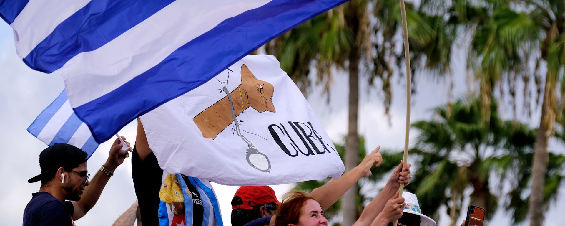 المهاجرون في ليتل هافانا يلوحون بالأعلام الكوبية أثناء ردهم على تقارير الاحتجاجات في كوبا ضد الاقتصاد المتدهور - سبوتنيك عربي, 1920, 13.07.2021