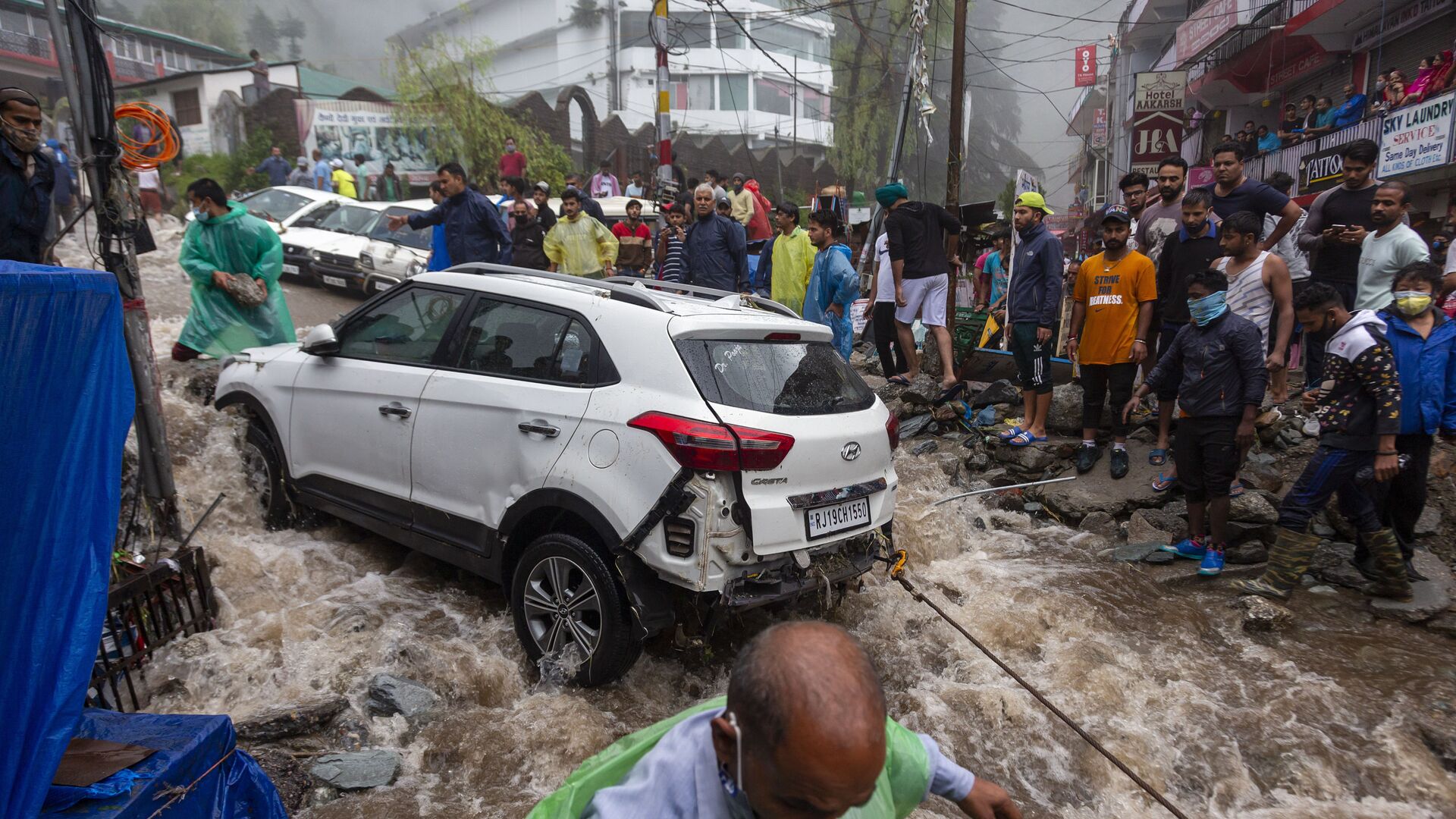 يحاول الناس استعادة سيارة تضررت خلال الفيضانات المفاجئة بعد هطول أمطار موسمية غزيرة في بهاغسوناغ، وهي بلدة سياحية شهيرة في هيماشال براديش، الهند، 12 يوليو 2021 - سبوتنيك عربي, 1920, 24.07.2021