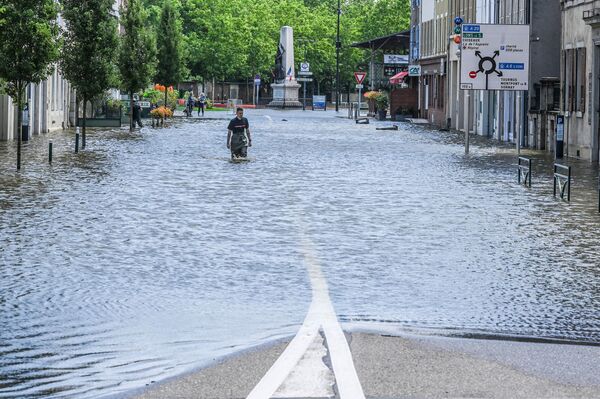 رجل إطفاء الحريق يسير وسط مياه الفيضانات في أحد شوارع لوهانس، فرنسا 17 يوليو 2021 - سبوتنيك عربي