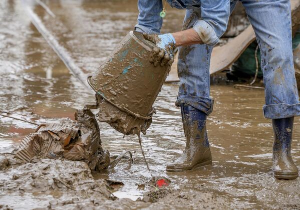 رجل يقوم بإزالة الوحل الناجم عن مياه الفيضانات في أحد شوراع بلدة باد نوينار-آرفايل، ألمانيا 17 يوليو 2021 - سبوتنيك عربي