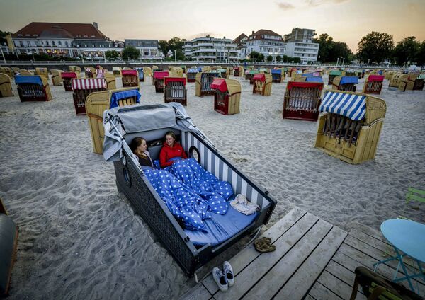 شابتان تستعدان لقضاء الليل داخل مقعد الشاطئ المصمم خصيصًا على شاطئ بحر البلطيق في ترافيمويندي، ألمانيا 18 يوليو 2021 - سبوتنيك عربي