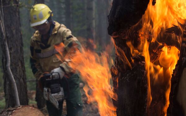 يقوم موظفو أفيا ليسو أوخرانا  لحراسة الغابات بمكافحة الحرائق لمنع انتشارها على نطاق أوسع في ياقوتيا، روسيا 11 يوليو 2021 - سبوتنيك عربي
