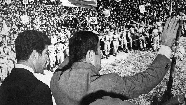 صورة غير مؤرخة تظهر الرئيس السوري حافظ الأسد (إلى اليمين) وهو يحيي الحشود في دمشق. يقف إلى جانبه الرئيس العراقي صدام حسين. - سبوتنيك عربي