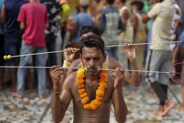 يستعد المخلصون، الذين تم ثقب خديهم بواسطة أعمدة حديدية كجزء من الطقوس المكرسة لبدء رحلة الحج السنوية إلى معبد الإلهة الهندوسية شيتلا ماتا في جامو، الهند، 25 يوليو 2021 - سبوتنيك عربي