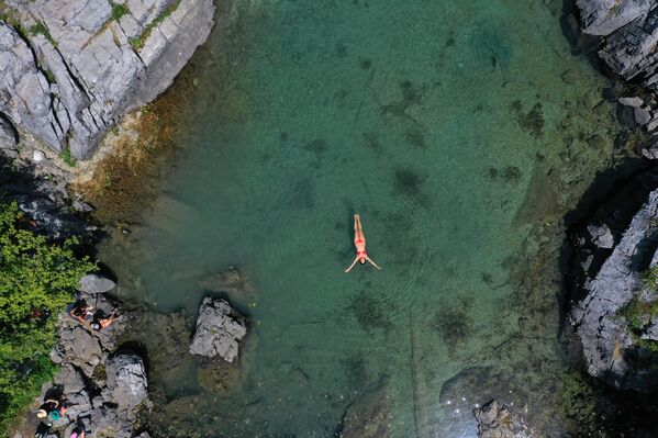 امرأة تسبح لتبرد في بحيرة كسيما، وهي بحيرة طبيعية صغيرة تقع في حديقة فالبونا الوطنية بالقرب من دراغوبي، 4 أغسطس 2021 - سبوتنيك عربي