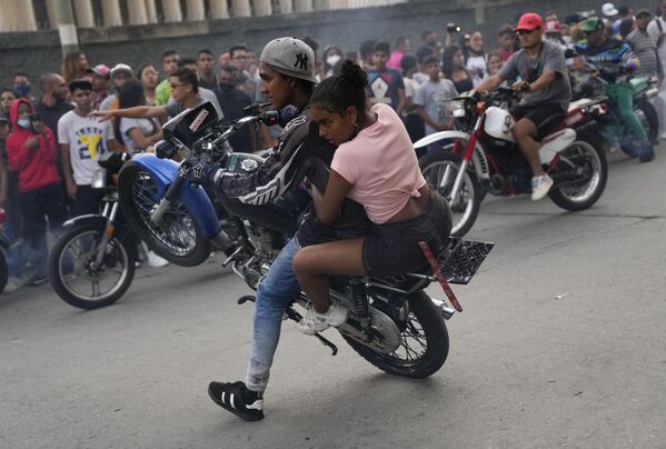 يقوم سائق دراجة نارية بحركة بهلوانية على دراجته النارية مع أحد الركاب خلال معرض في حي إل فالي في كاراكاس ، فنزويلا ، 31 يوليو 2021 - سبوتنيك عربي