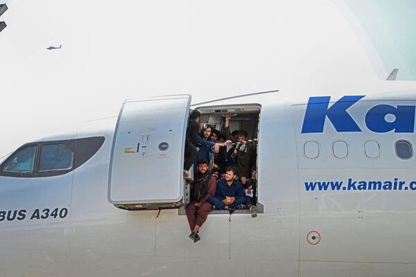 أفغان يجلسون على باب طائرة في مطار كابول - سبوتنيك عربي