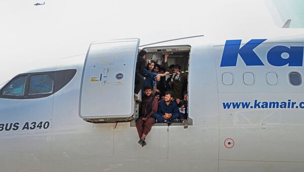أفغان يجلسون على باب طائرة في مطار كابول - سبوتنيك عربي
