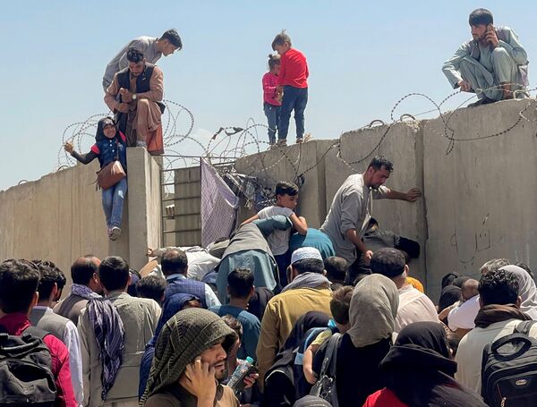 رجل يرفع فتاة إلى أعلى السور في مطار كابول - سبوتنيك عربي