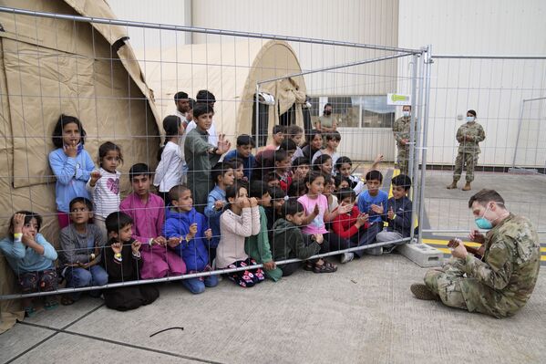 جندي أمريكي يعزف على الغيتار لأطفال أفغانيين تم إجلاءهم من أفغانستان إلى القاهعدة الجوية رامشتين في ألمانيا 24 أغسطس 2021 - سبوتنيك عربي