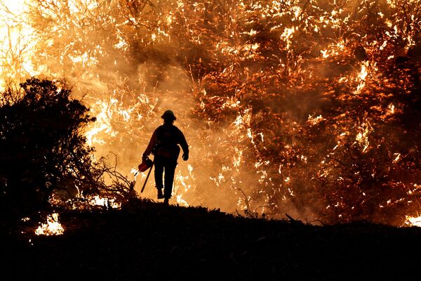 رجل إطفاء يسير على خلفية اشتعال حريق كالدور في جريزلي فلاتس، ولاية كاليفورنيا، الولايات المتحدة 22 أغسطس 2021 - سبوتنيك عربي