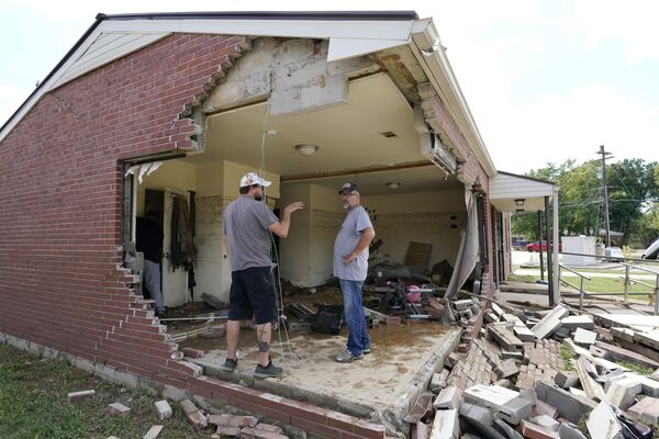 بريان ميتشل (يمين الصورة)  ينظر من خلال منزل حماته المتضرر مع صديق العائلة كريس هوفر (يسار الصورة) في ويفرلي، ولاية تينيسي، الولايات المتحدة، 22 أغسطس 2021 - سبوتنيك عربي